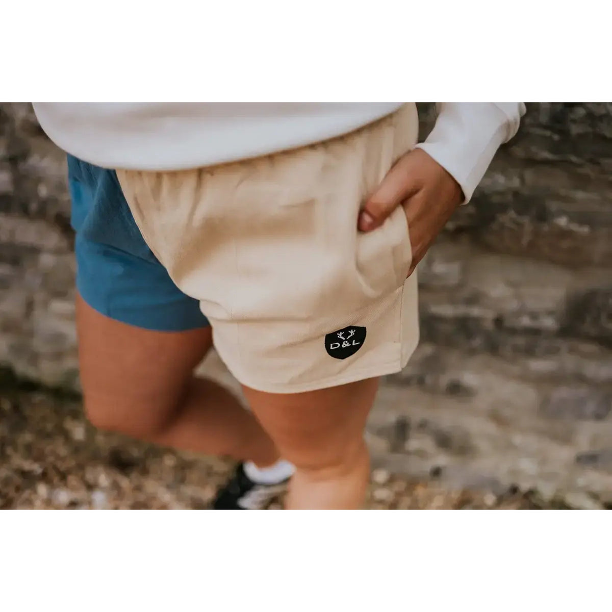 Blue and cream rugby shorts shown worn, with a close-up of the cream panel and D&L badge.