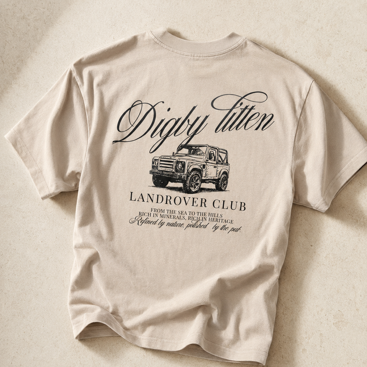 Beige Land Rover Club T-Shirt laid flat, showing the vehicle graphic and lettering on the back.